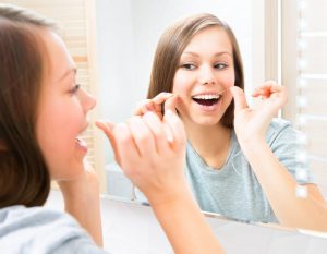 Flossing in the bathroom mirror